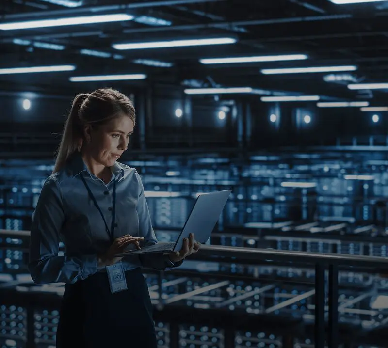 Woman using laptop in data center.