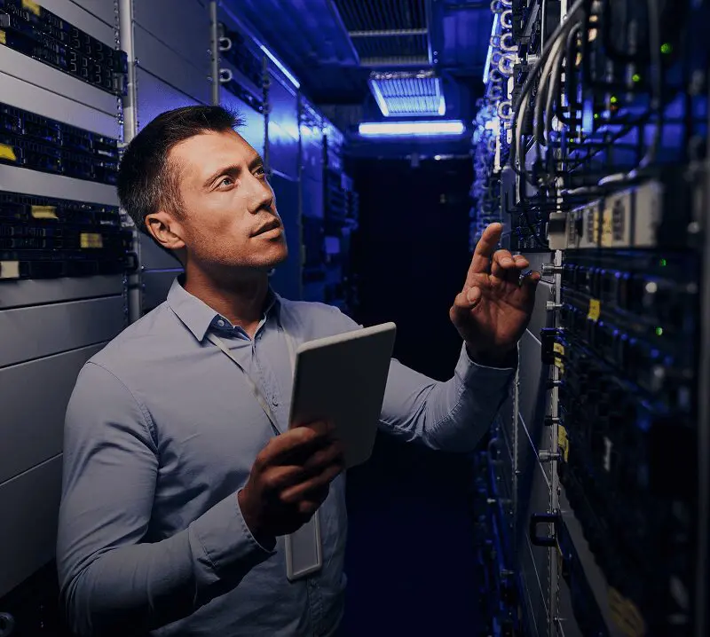 Technician inspecting servers with tablet in hand.