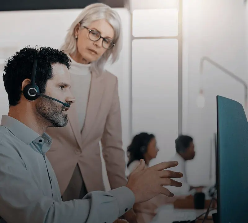 Man with headset and woman at computer.
