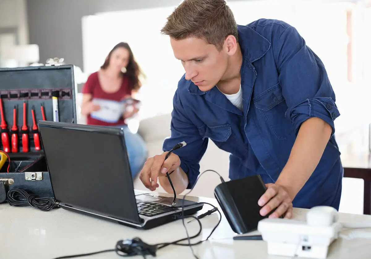 Man repairing laptop with tools nearby.